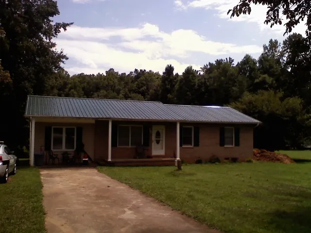 Dark green metal roof on a brick ranch with a covered porch in Philadelphia