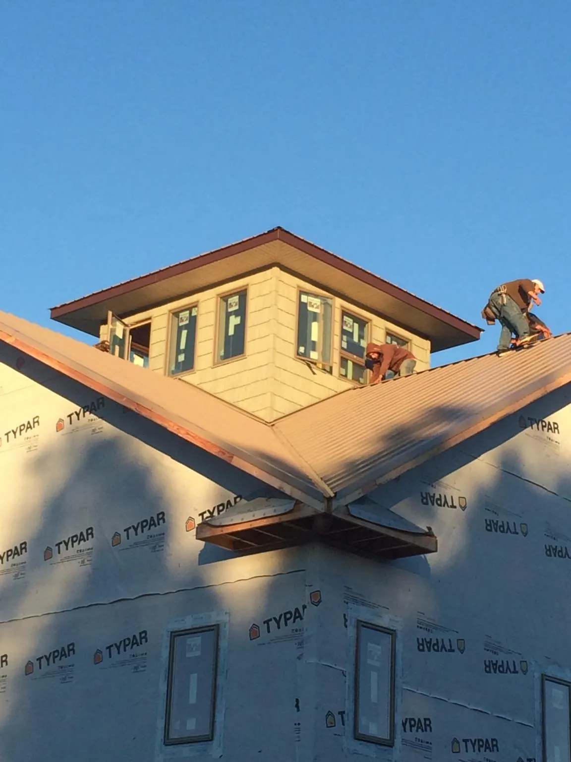 Roofers working around a rooftop cupola on a new metal roof at sunset — Roof Waterproofing in Philadelphia by Roofing Brothers